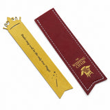 A gold-colored metal bookmark shaped like a crown with the quote 'Books may need to be the only true Magic' engraved, shown next to its dark red fabric sleeve with white stitching and gold lettering that reads 'THE WISHING CHAIR'.